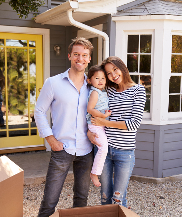 Proud family of three posing outside new owner-built home